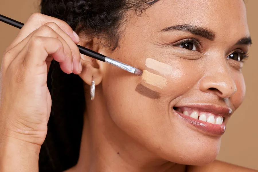 A woman color testing foundation on her cheek.